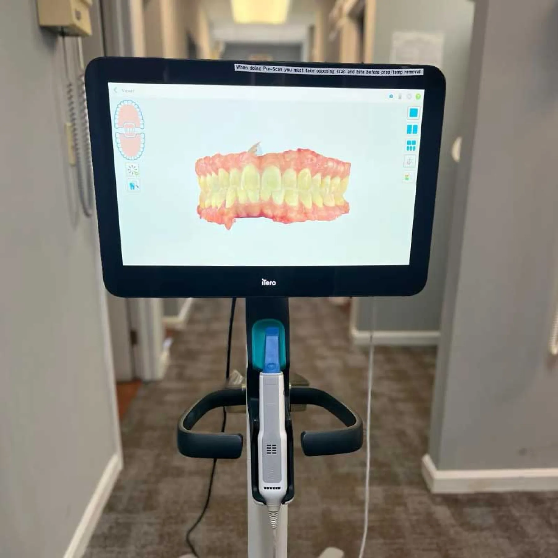 Dental imaging device displaying a 3D model of teeth and gums in a clinic setting.